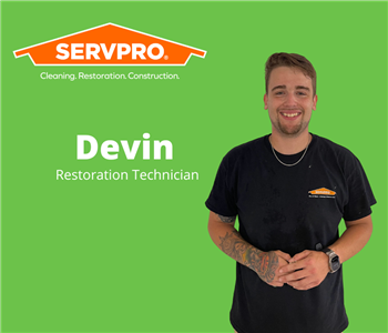 Male servpro employee standing in front of a green background with a Servpro logo
