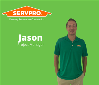 Male servpro employee standing in front of a green background with a Servpro logo